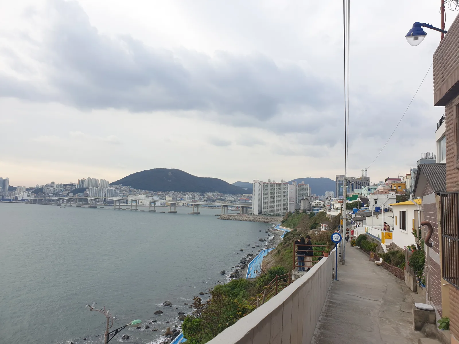 좁은 골목 사이로 마을 안내 간판이 걸린 노란 건물이 보이는 흰여울문화마을 골목