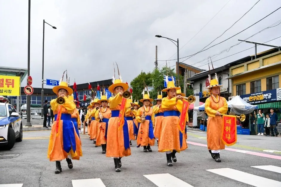 주황색과 파란색 한복 차림 행렬이 도로를 지나는 풍기인삼축제 퍼레이드