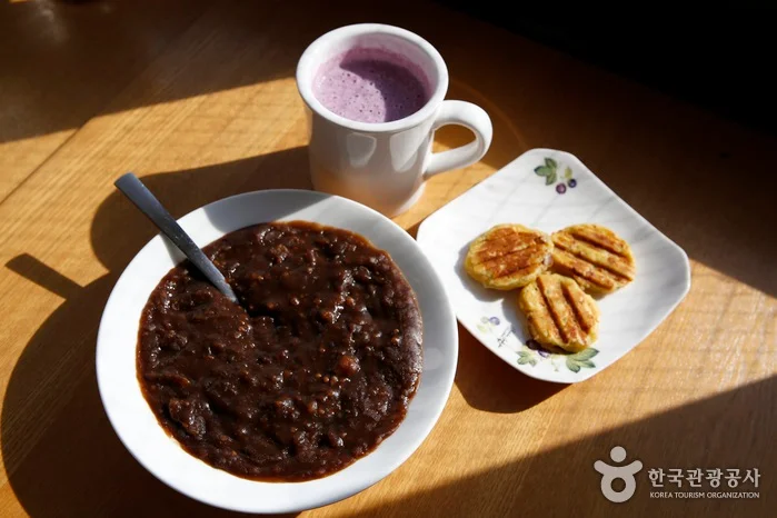 빼떼기죽과 고구마 부침, 보랏빛 음료가 놓인 나무 식탁