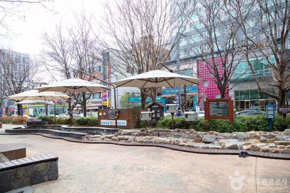 파라솔과 돌 수로가 있는 족욕체험장 옆 휴식 공간